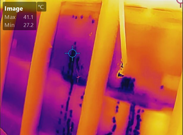 Thermal image of a loft showing cooler wet roof felt beneath a solar panel array, traced during a leak investigation in Kingskerswell, Devon