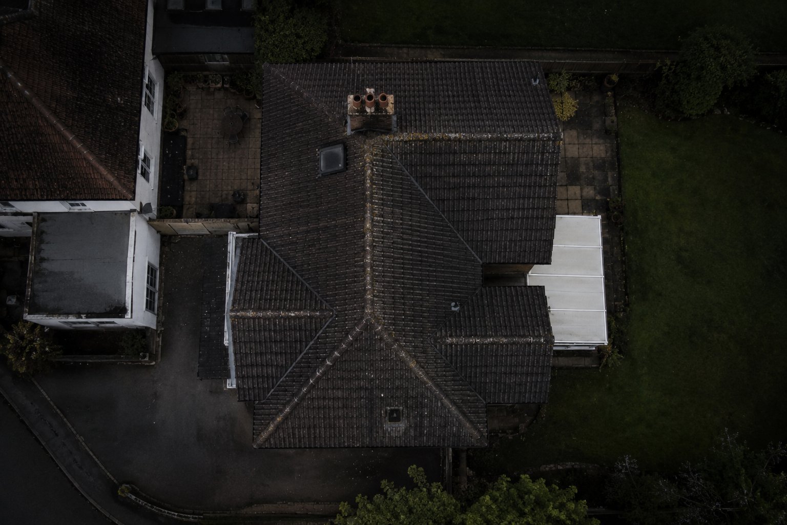 Aerial drone view of a tiled domestic roof showing ridge lines, chimney and valleys